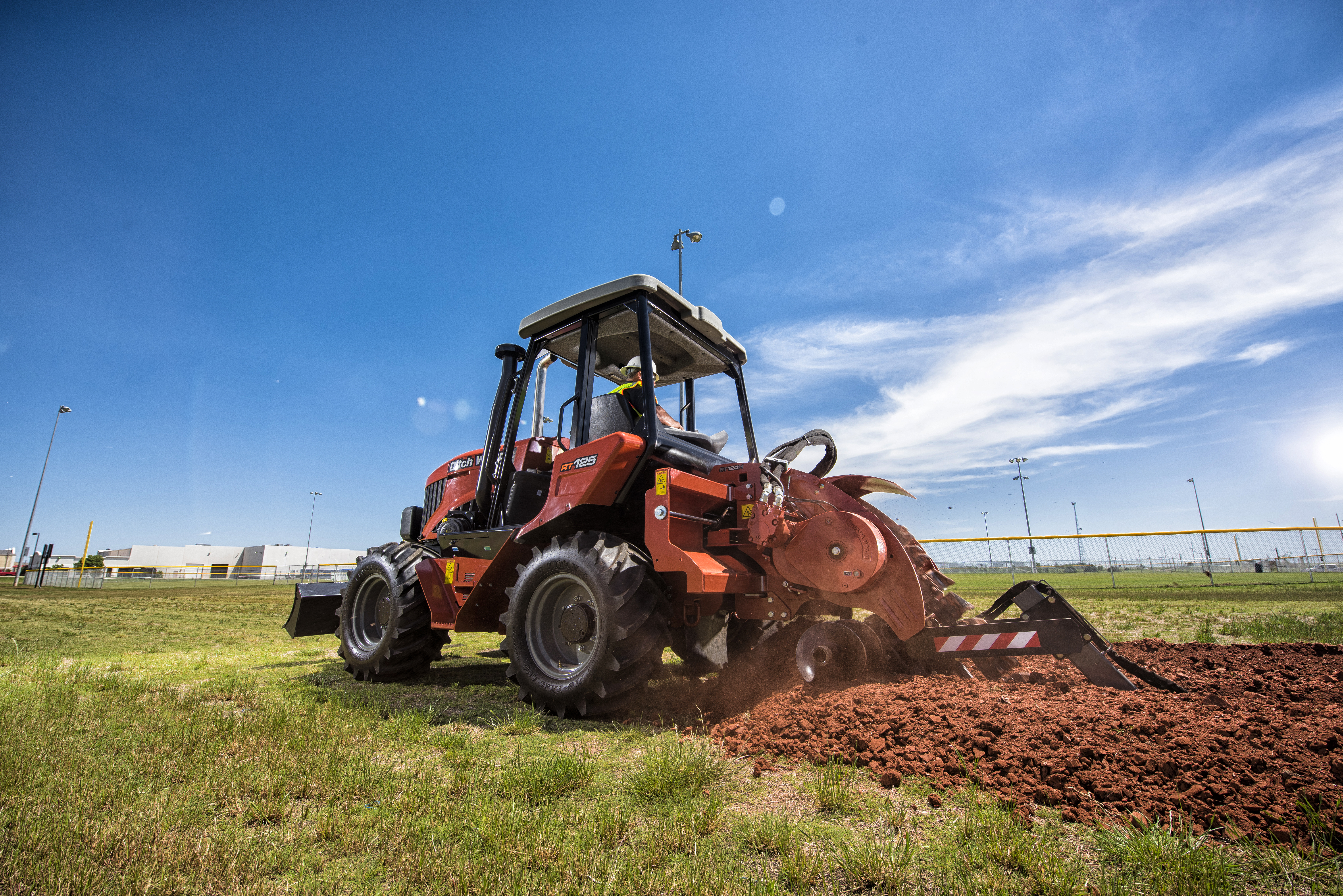 Ditch Witch RT125 ride-on trencher digging long utility trenches in open terrain.
